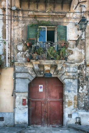 vintage balcony with different flowers, cracked plaster and wooden doors, Mediterranean style on island Sicily, Italyの写真素材