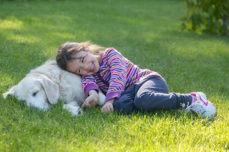 A little girl with her pet dog outdoors in gardenの写真素材