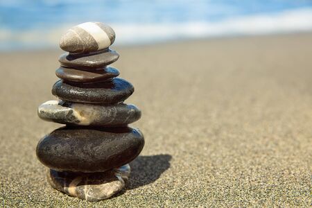 Stones pyramid on sand symbolizing zen, harmony, balance. Ocean in the backgroundの写真素材