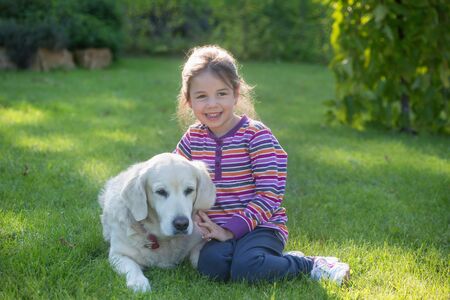 A little girl with her pet dog outdoors in garden