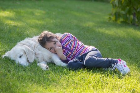 A little girl with her pet dog outdoors in gardenの写真素材