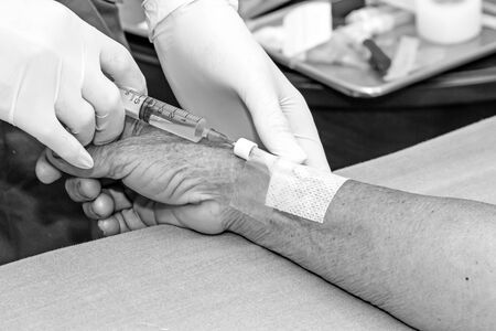 Doctor push syringe in heparin plug hand of patientの写真素材