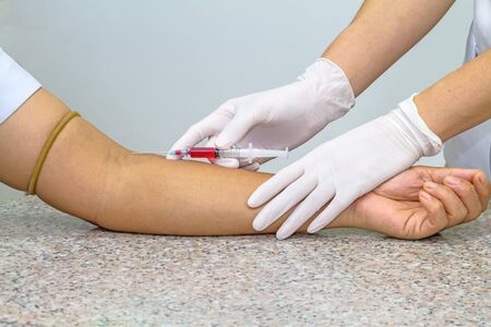 Blood test from venous vein  of patient by female doctor in white medical gloves on   the marble...