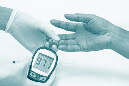blood glucose meter, the blood sugar value is measured on a finger by  female doctor in white medical glovesの写真素材
