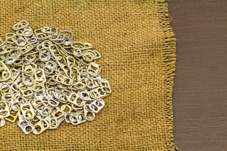 Ring pull aluminum of cans aluminium plastic use for prosthetics in  brown sack fabric  on black...