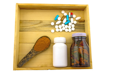 Assorted  bottle medicine and turmeric powder in wooden spoon  in wood box on white backgroundの写真素材