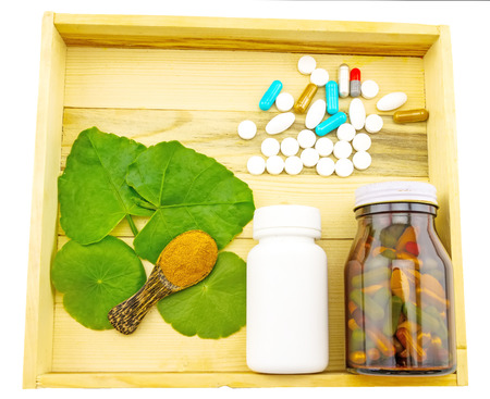 Assorted  bottle medicine  , green leaf of  Asiatic Pennywort and turmeric powder in wooden spoon   in wood box on white backgroundの写真素材