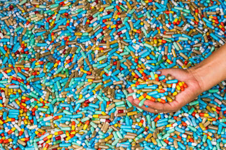 Hand of man show many colorful medicines expire on cement floor