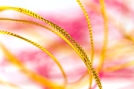 Close up disorganized pile of pink and gold  rope on white background