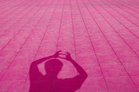 Shadow of man who show extend the fingers heart-shape on blue rubber flooring of Futsal field...