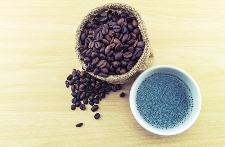 Sweet basil in white cup and coffee beans in sack sisal on wooden background.の写真素材