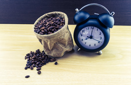 vintage classic alarm clock and coffee beans in sack sisal on wooden tableの写真素材