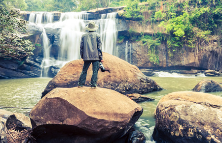 The man standing with camera at Tad Huang Waterfall the most beautiful of Phu Suan Sai, become the murder line between Thai-Laos, water fall in deep forest at at Phu Suan Sai National Park, Loei Province,processed in vintage styleの写真素材