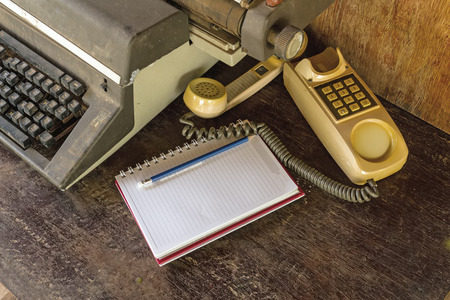 Vintage typewriter ,white  book,  ,pencil and old telephone on old wooden touch-up in still life conceptの写真素材