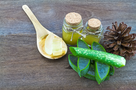 Fresh aloe vera gel on wooden  spoon with aloe  vera essential oil and pine  on wooden tableの写真素材
