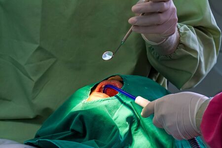 Hand of dentist examining a patient's teeth in the hospital.
