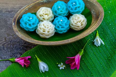Traditional Thai dessert flower shape stuff with crush soybean and taro (Thai name kanom Chor phaka) in wooden basket on bana leaf.の写真素材