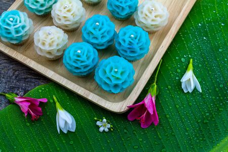 Traditional Thai dessert flower shape stuff with crush soybean and taro (Thai name kanom Chor phaka) in wooden basket on bana leaf.の写真素材