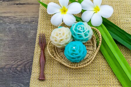 Traditional Thai dessert flower shape stuff with crush soybean and taro (Thai name kanom Chor phaka) in bamboo basket on fabric background.の写真素材