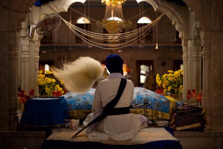 Paonta Sahib - May 23: A Sikh man waves a fluffy wand at an ornately carved and decorated altar inside the Paonta Sahib gurudwara's prayer hall May 23, 2009 at Paonta Sahib, Himachal Pradesh, Indiaのeditorial素材
