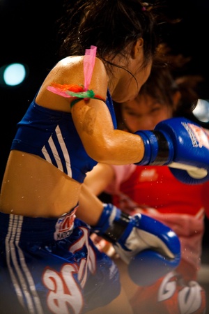 BANGKOK - OCTOBER 12: A female muay thai boxer receives a kick sending sweat flying through the air at Fight Night October 12, 2010 at Bangkok, Thailandのeditorial素材