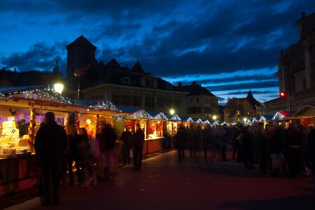 Temporary wooden chalets form a market selling regional products, an annual tradition during the Christmas season in Annecy, France.  The old town, palais de l'isle, and castle are in the background.のeditorial素材