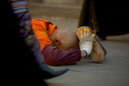 Lhasa, Tibet, China - October 17, 2007: A Tibetan Buddhist man in full prostration on the ground surrounded by other pilgrims at the Barkhor, a focal point of Tibetan pilgrims, on October 17, 2007 in Lhasa, Tibet.のeditorial素材