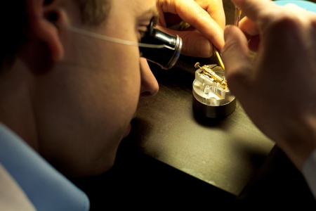 Geneva, Switzerland - November 13:  A Swiss watchmaker concentrates on assembling fine internal parts of a watch during The Watches Day, an annual exhibition of Swiss watchmakers November 13, 2011 at Geneva, Switzerlandのeditorial素材