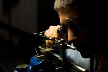 Geneva, Switzerland - November 13: A Swiss watchmaker grinds down a hand-made watch part during The Watches Day, an annual exhibition of Swiss watchmakers November 13, 2011 at Geneva, Switzerland.  Horizontalのeditorial素材