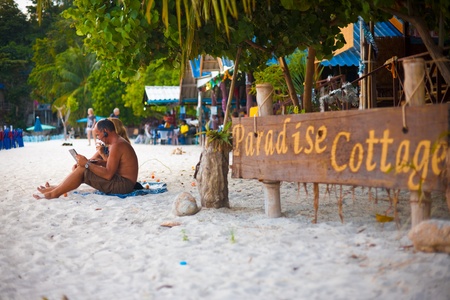 KO LIPE, THAILAND - JANUARY 24, 2010: A man connects to the internet to video call while on a beautiful beach on January 24, 2010 in Ko Lipe, Thailand. Life today requires people to be connectedのeditorial素材