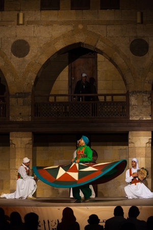 CAIRO, EGYPT - JULY 3, 2010: A Sufi dancer in green spins during a whirling dervish performance, a famous tourist attraction, at an open air courtyard in Cairo, Egypt on July 3, 2010. Verticalのeditorial素材