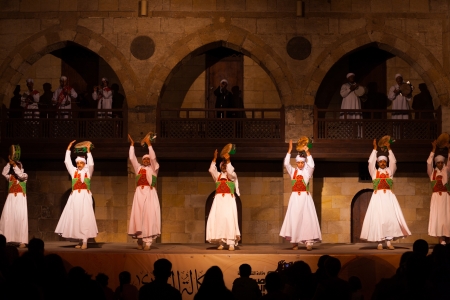 CAIRO, EGYPT - JULY 3, 2010: A row of Sufi dancers in white play tamborine during a whirling dervish performance, a famous tourist attraction, at an open air courtyard in Cairo, Egypt on July 3, 2010のeditorial素材