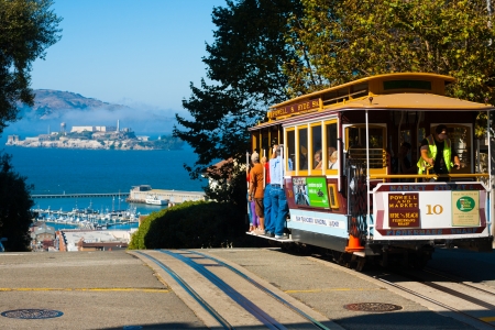 SAN FRANCISCO, USA - SEPTEMBER 21, 2011: Powell Hyde cable car, an iconic tourist attraction, descends a steep hill overlooking Alcatraz prison and SF bay on September 21, 2011 in San Francisco, USAのeditorial素材