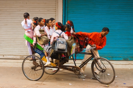 DELHI, INDIA - OCTOBER 27, 2009: Young girls ride a crammed private cycle rickshaw to school on October 27, 2009 in Delhi, India. Schools do not provide shared bus transportation in India.のeditorial素材