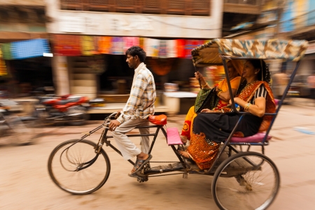 MATHURA, INDIA - NOVEMBER 13, 2009: Two Indian women laugh riding a cycle rickshaw, a popular form of taxi, through a busy bazaar on November 13, 2009 in Mathura, Indiaのeditorial素材
