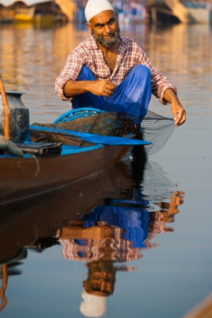 SRINAGAR, INDIA - JULY 11, 2009: A Muslim fisherman in a canoe prepares his net to go fishing on Dal Lake on July 11, 2009 in Srinagar, India. Fishing is an old traditional occupation on Dal Lakeのeditorial素材