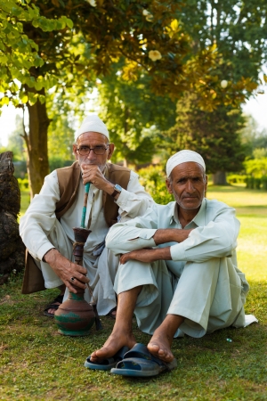 SRINAGAR, INDIA - JULY 9, 2009: Unidentified Kashmiri muslim men sit in the beautiful nature of Kashmir smoking a shisha in the outdoors on July 9, 2009 in Srinagar, Indiaのeditorial素材