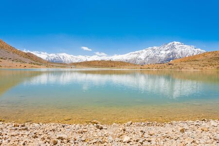 A pristine alpine lake reflects the surrounding Himalayan mountains. The lake is a pilgrimage point...