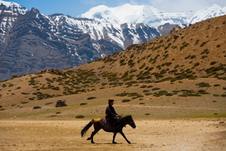 DHANKAR, INDIA - JUNE 7, 2009: An unidentified Buddhist man rides a horse on pilgrimage 3 times around a holy lake among the Himalayan mountains in the Spiti Valley on June 7, 2009 in Dhankar, Indiaのeditorial素材