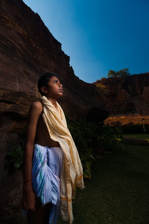 BADAMI, INDIA - February 23, 2009: A young boy Brahmin priest stands waiting for the end of a puja prayer at the base of the cave temples on February 23, 2009 in Badami, Indiaのeditorial素材