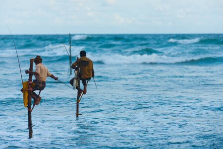 UNAWATUNA, SRI LANKA - MAY 22, 2008: Unidentified Sri Lankan stilt fishermen fish for small catch in a traditional way surrounded by a wide ocean on May 22, 2008 in Unawatuna, Sri Lanka. Copy spaceのeditorial素材