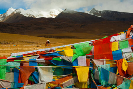 A beautiful natural mountain landscape behind a traditional Tibetan oven and a mass of prayer flags in Tibet, Chinaの写真素材