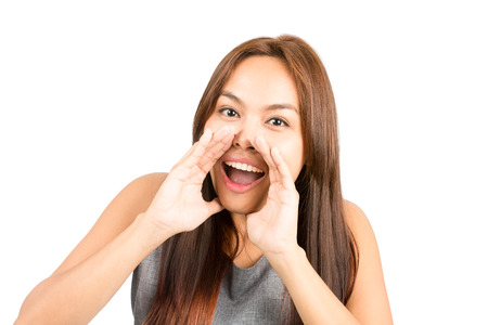 Portrait of good looking Asian girl, sleeveless top, light brown hair shouting announcement looking...