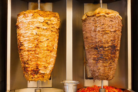 Delicious slabs of skewered fast food shawerma chicken and lamb meat turn side by side on a spit. This is common sandwich meat found in fast food in the Middle East.の写真素材