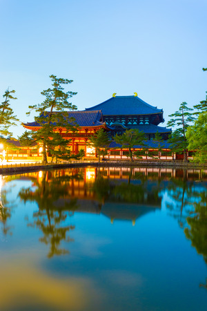 Haunting long exposure of front entry gate and Daibutsuden Great Buddha Hall reflected in a still pond at night in Todai-ji temple in Nara, Japanのeditorial素材