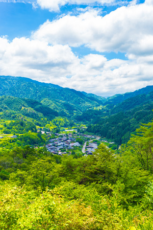 A view from high angle viewpoint and former grounds of Tsumago castle overlooking Tsumago village above the Magome-Tsumago portion of ancient Nakasendo Route in Japan on a blue sky day. Verticalの写真素材