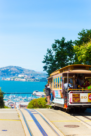 San Francisco, USA - May 15, 2016: An iconic cable car full of passengers at the crest of Hyde Street going over the edge toward the view of Alcatraz Island in the bay. Verticalのeditorial素材