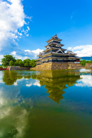Blue sky clouds and the ancient keep of Matsumoto Castle is reflected beautifully in moat water in Nagano Prefecture, Japan. Verticalのeditorial素材