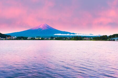 Fiery colorful sky above the red crater cone of Mount Fuji at dawn sunrise over Lake Kawaguchiko water on a summer morning in Japanの写真素材