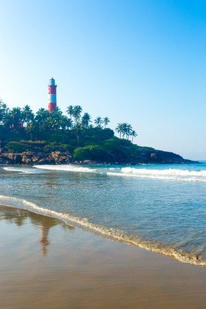 Lighthouse standing above the rocky outcrop above the ocean waves at Kovalam Beach in Kerala, India. Verticalの写真素材